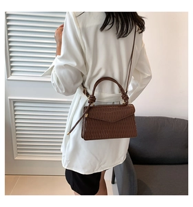 Macro view of dark brown pleated PU leather texture with gold hardware on a chic small bag