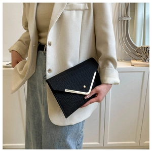 Close-up of black crocodile pattern envelope clutch with gold V-shaped metal trim