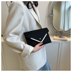 Detail of black faux leather envelope clutch with gold V-metal trim and croc texture