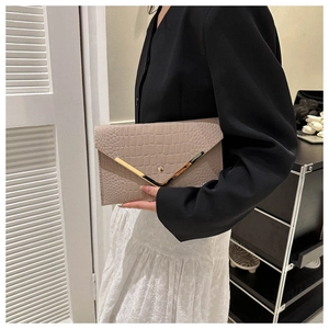 Detail of nude crocodile embossed envelope clutch with gold V-shaped metal trim