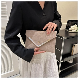 Detail of nude crocodile pattern envelope clutch featuring elegant V-shaped metal trim