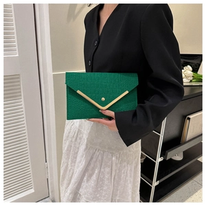 Detail of emerald green envelope clutch featuring crocodile pattern and V-shaped gold trim