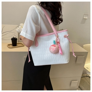 Detail of white quilted tote bag with pink straps and a peach plush charm detail