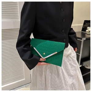 Detail of emerald green crocodile pattern envelope clutch with stylish metal trim
