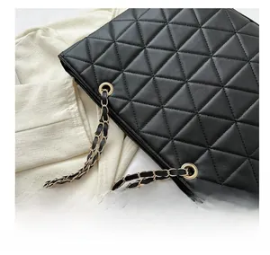 Detail of black quilted leather tote bag featuring gold chain strap and fine stitching