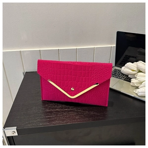 Detail of rose red envelope clutch with crocodile texture and gold V-shaped trim