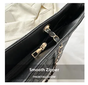Close-up of smooth gold-tone zipper and quilted black leather on a large tote bag