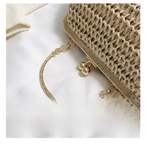Dettaglio borsa a conchiglia in paglia beige con chiusura a bacio e manico intagliato