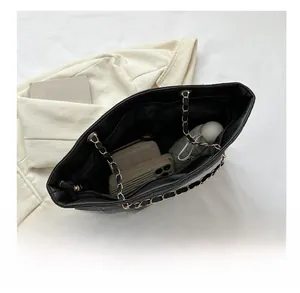Top view showing the spacious interior of a black quilted tote with chain straps