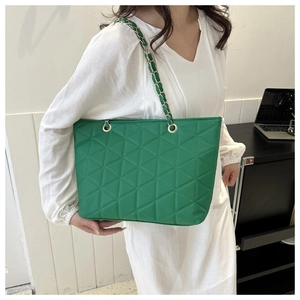 Close-up of emerald green quilted tote bag with triangle stitching and chain strap