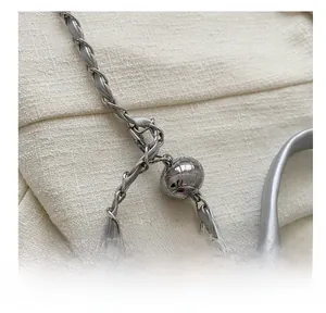 Detail of silver chain strap with quilted metal ball buckle adjustment on leather bag