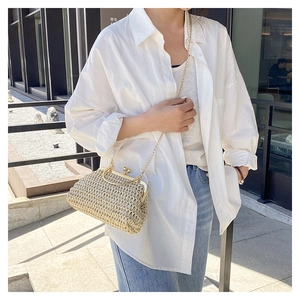 Dettaglio borsa a tracolla intrecciata beige con chiusura metallica e catena dorata