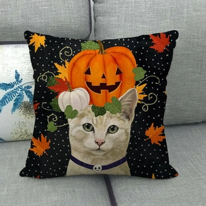Détail de la housse de coussin Halloween avec chat et citrouilles sur un canapé gris