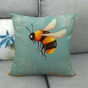 Detail of artistic bee pattern cushion cover on a grey sofa with linen texture fabric