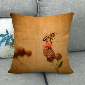 Detail of vintage linen pillow cover featuring a honeybee and thistle on a sofa