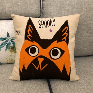 Close-up of linen Halloween pillowcase with cartoon spooky cat on a gray sofa