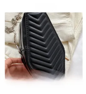Detail view of coffin-shaped quilted crossbody bag with silver chain and metal zipper