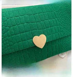 Detailed close-up of emerald green crocodile texture with a gold heart-shaped metal buckle