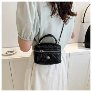 Détail du mini sac seau matelassé noir avec fermoir fleur et bandoulière chaîne
