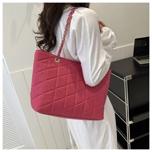 Detail of rose pink quilted tote bag with gold chain strap on a model shoulder