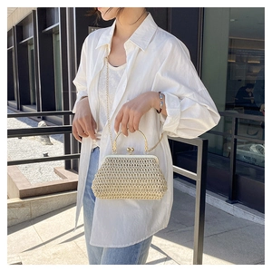 Dettaglio borsa in paglia intrecciata beige con manico tondo d'oro e chiusura a sfera