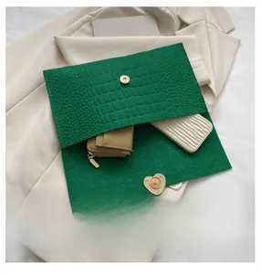 Detail view of the green crocodile embossed envelope bag showing spacious interior capacity