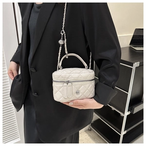 Détail du mini sac seau blanc matelassé avec bandoulière chaîne et emblème floral