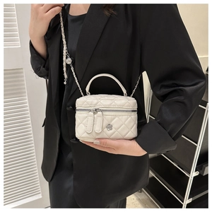 Gros plan du mini sac blanc matelassé avec bandoulière chaîne et détail fleur en métal