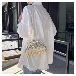 Dettaglio borsa in paglia intrecciata beige con chiusura in metallo oro e catena