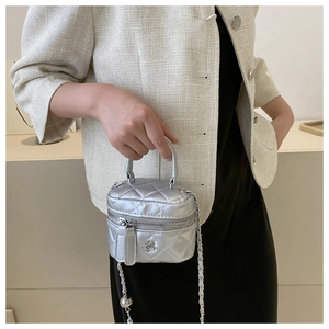 Vue détaillée du mini sac argenté matelassé avec breloque fleur et bandoulière en chaîne