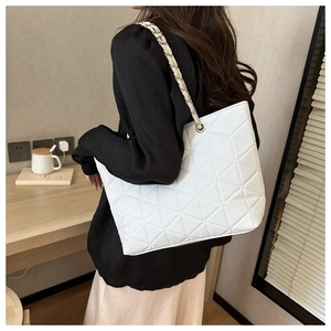 Detail view of white quilted tote bag with triangle stitching and woven chain strap