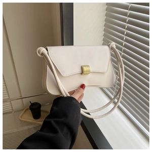Close-up of white minimalist shoulder bag featuring a gold square buckle and rope strap