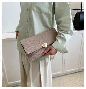 Detail of taupe crocodile texture envelope clutch with gold heart-shaped buckle