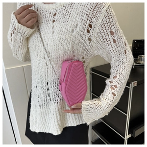 Detail of pink coffin-shaped crossbody bag with chevron quilting and silver chain strap