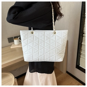 Close-up of quilted pattern and gold chain strap on a white tote bag for women