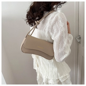 Detail of beige shoulder bag featuring a knotted strap and gold fashion branding text