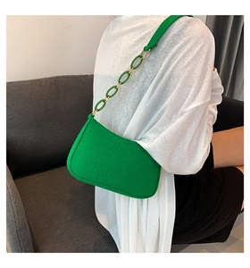 Detail of green felt crossbody bag featuring textured fabric and decorative chain strap