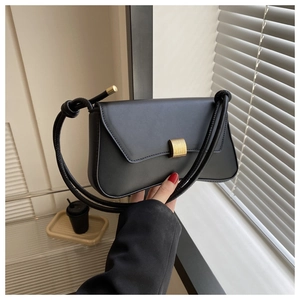 Detail of minimalist black baguette bag with elegant gold metal buckle and cord shoulder strap