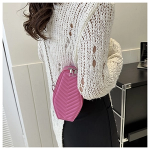 Detailed view of pink coffin-shaped crossbody bag with V-quilt pattern and chain strap