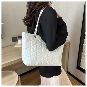 Detail of white quilted tote bag with triangle stitching and metal chain shoulder strap
