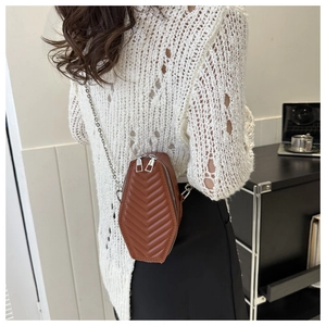 Close-up of a brown coffin-shaped crossbody bag with V-shaped quilting and silver chain strap