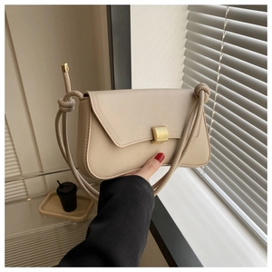 Detail of beige leather bag featuring textured gold buckle and decorative knot strap