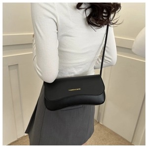 Close-up of black matte leather shoulder bag with golden Fashion text and slim strap