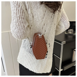 Rear view of brown quilted coffin-shaped crossbody bag with silver chain strap on model