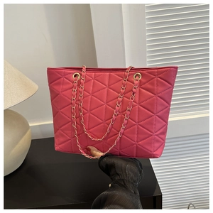 Detail of fuchsia tote bag featuring triangle quilted pattern and golden chain strap