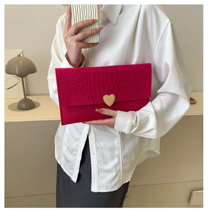 Hot pink crocodile textured envelope clutch featuring a gold heart clasp held by a model