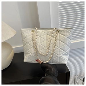 Detail of white quilted tote bag with gold chain strap and textured leather finish