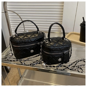 Detail of two black quilted mini cosmetic bags with silver chain and flower charm