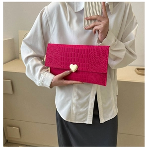 Detail of fuchsia envelope clutch with crocodile texture and gold heart-shaped metal buckle
