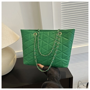 Detail of green quilted tote bag with golden chain strap and rhombus stitching texture